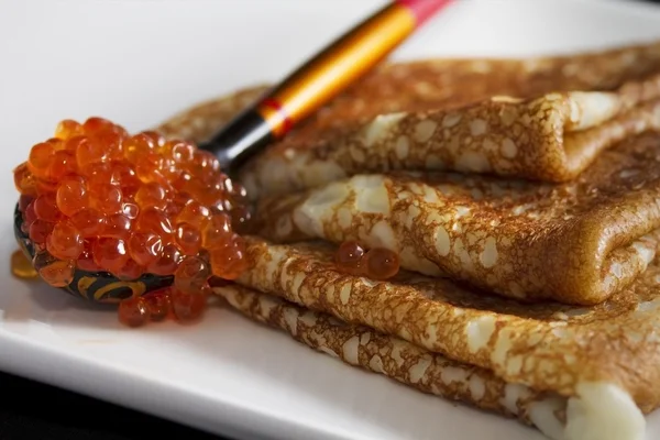 Pancakes and a wooden spoon with red caviar — Stock Photo, Image