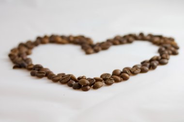 Heart laid out roasted coffee beans on a white background clipart