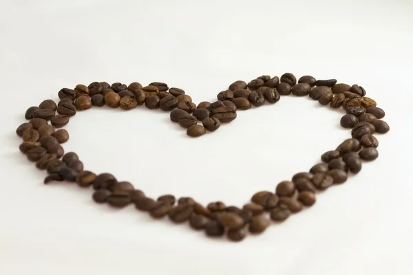 Coração colocado grãos de café torrados em um fundo branco — Fotografia de Stock