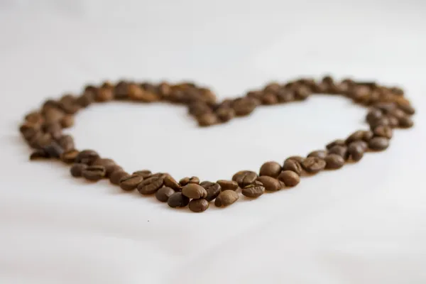 Coração colocado grãos de café torrados em um fundo branco — Fotografia de Stock