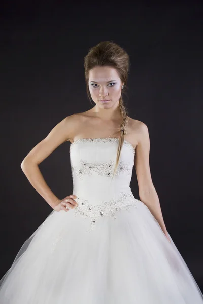 Young beautiful girl in a wedding dress on a dark background — Stock Photo, Image