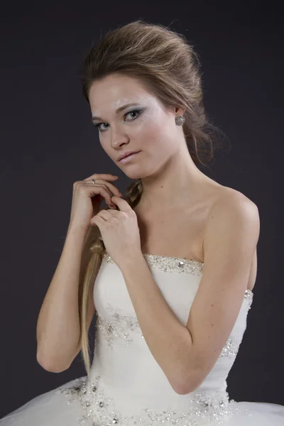 Young beautiful girl in a wedding dress on a dark background — Stock Photo, Image