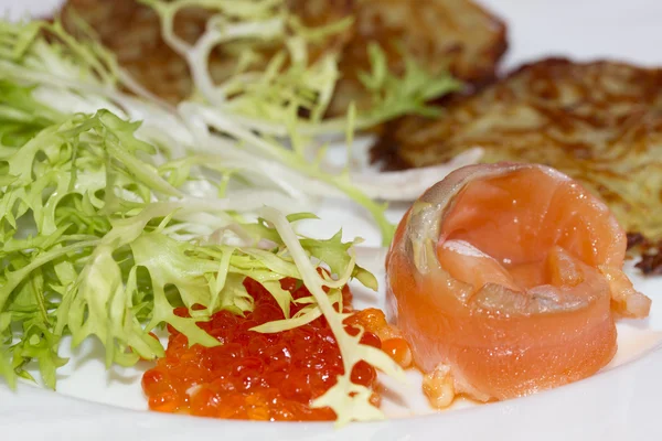 Frittelle di patate su un piatto con un pezzo di salmone e caviale rosso — Foto Stock