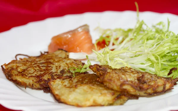 Frittelle di patate su un piatto con un pezzo di salmone e caviale rosso — Foto Stock