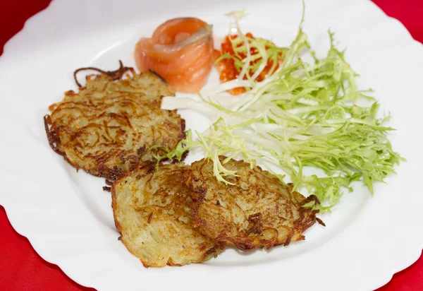 Frittelle di patate su un piatto con un pezzo di salmone e caviale rosso — Foto Stock