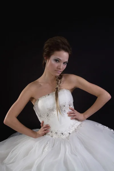 Young beautiful girl in a wedding dress on a dark background — Stock Photo, Image