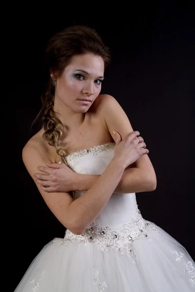 Young beautiful girl in a wedding dress on a dark background — Stock Photo, Image