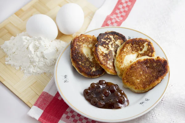 Clătită cheag pe o farfurie cu gem de căpșuni și o mână de făină și ou — Fotografie, imagine de stoc