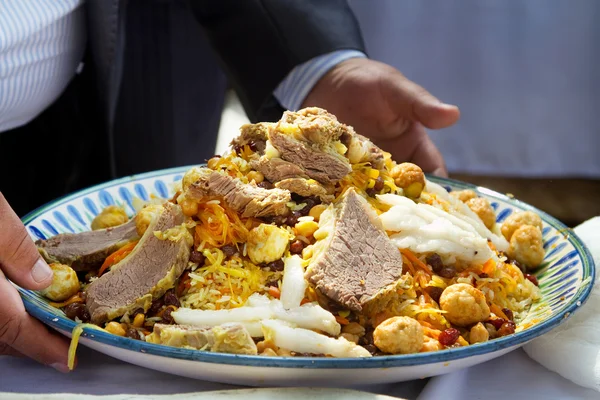 Een groot bord Buchara pilaf in mannelijke handen — Stockfoto