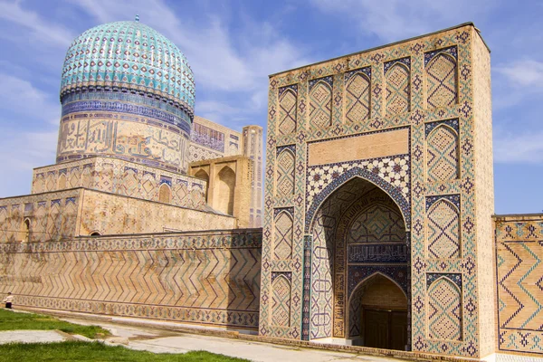 Um grande portão e uma torre com uma cúpula de uma antiga madrassa em Samarcanda, Uzbequistão — Fotografia de Stock