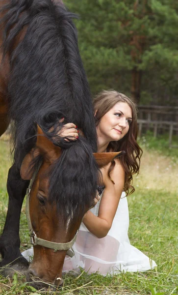 Beautiful girl in a long white skirt with a brown horse — Stock Photo, Image