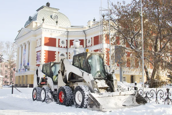Snow Removendo minitractor no fundo do edifício de teatro em Irkutsk Fotos De Bancos De Imagens