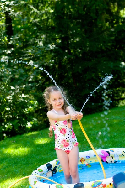 Little girl playing in pool under water splashes — Stock Photo, Image