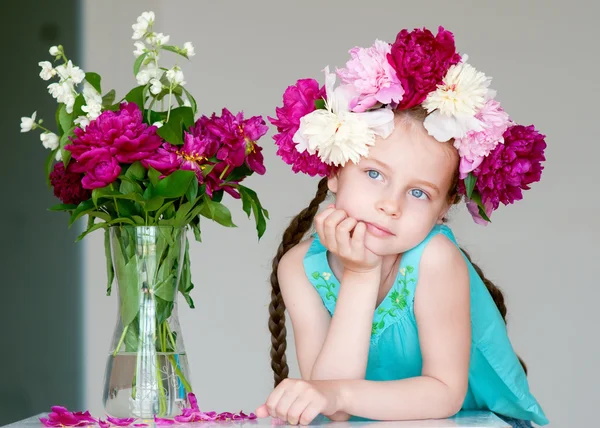 Entzückendes kleines Mädchen mit Kranz aus Pfingstrosenblumen Stockbild