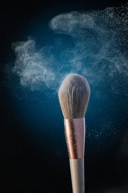 Kozmetik fırçayla siyah arkaplanda toz bulutu