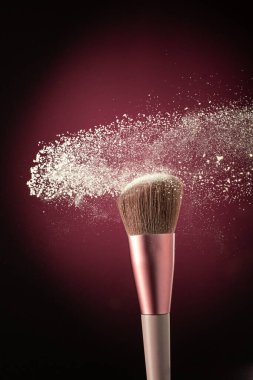 Kozmetik fırçayla siyah arkaplanda toz bulutu