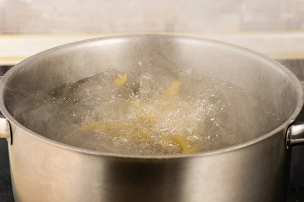 スパゲティパスタを沸騰したお湯の金属鍋に入れて — ストック写真