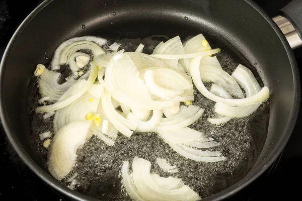 把切碎的洋葱圈放在蔬菜葵花籽油中放在特氟纶锅里煎 — 图库照片
