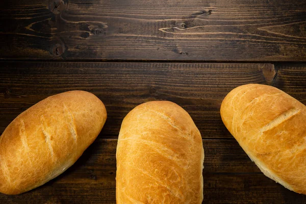 Färska Bakade Bröd Ligga Ett Mörkt Träbord — Stockfoto