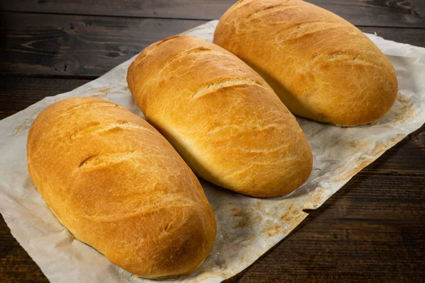 Koyu ahşap bir masanın üzerinde taze ekmek somunları yatıyor.