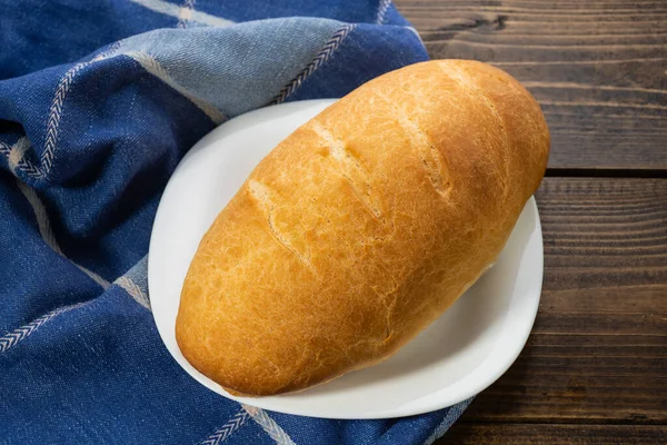 Koyu ahşap bir masanın üzerinde taze ekmek somunları yatıyor.