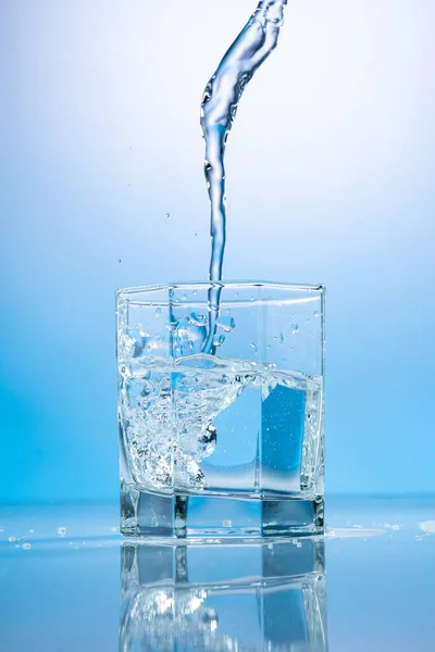 Salpicadura Agua Vaso Transparente Sobre Fondo Azul — Foto de Stock