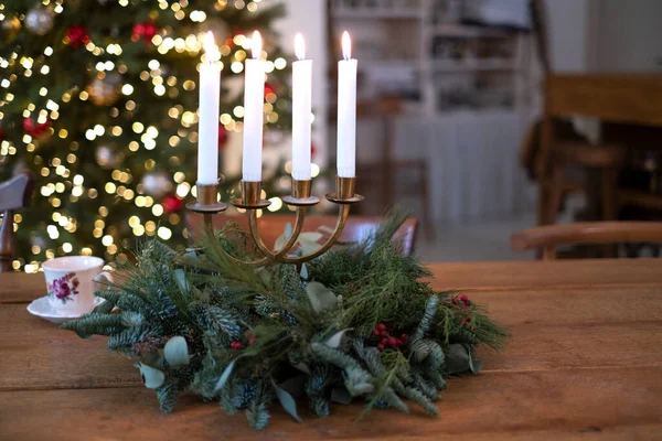 Noel ağacının yanındaki masada mum yaktım. Tüketim tatili, yeni yıl ve Noel, ev konforu