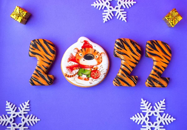 Yeni yılın sembolü şeklinde kurabiyeler. Çizgili sayılar ve boyalı bir kaplan. Mor bir arka planda
