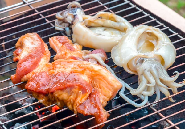 Trozo de carne de cerdo cruda y calamar en la parrilla de barbacoa de carbón —  Fotos de Stock