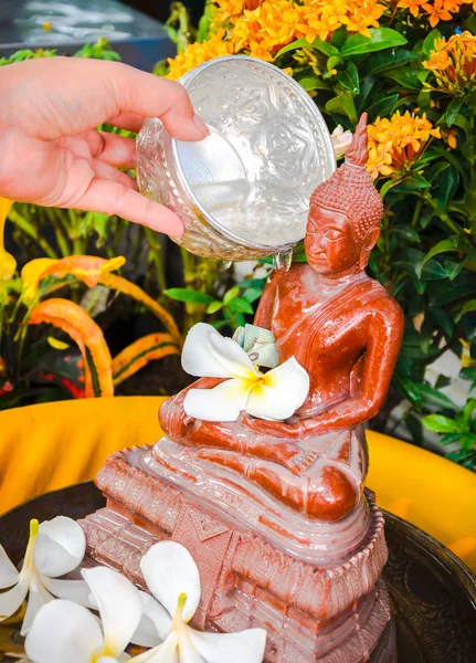 Human hand watering the Buddha statue — Stock Photo, Image