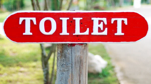 Rotes hölzernes öffentliches Toilettenschild — Stockfoto