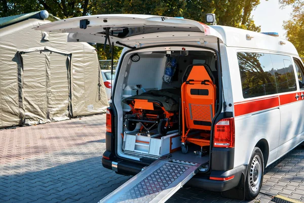 Opened back door of ambulance vehicle, bright orange carrying stretcher and chair visible — Stock Photo, Image
