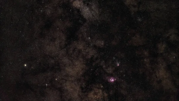 射手座の近くの天の川の夜空、明るいKaus Borealis星とM22の球状星団が左側に見え、紫色のラグーンとトリフィド星雲が見えます。長時間露光積層写真 — ストック写真