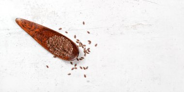 Yaygın keten tohumu - Linum usitatissimum - beyaz taş tahtaya yerleştirilmiş küçük ahşap kepçe üzerine tohum - sağ tarafta metin için boşluk ile geniş pankart