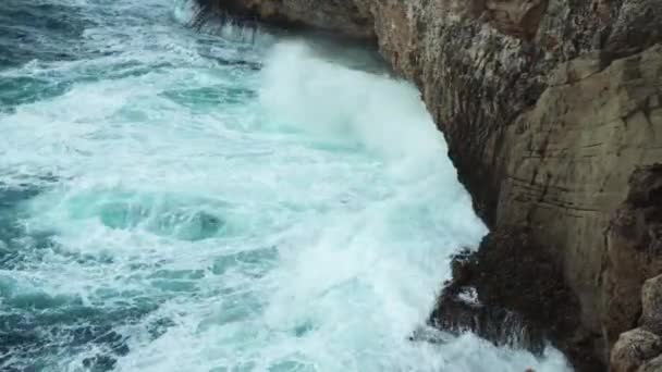 海は岩の多い海岸に衝突し 緑色の水が飛び散り 白い泡を作り出し 上からの眺め — ストック動画