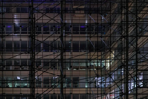 IJzeren steiger constructie rond staal en glas modern kantoorgebouw in de nacht — Stockfoto