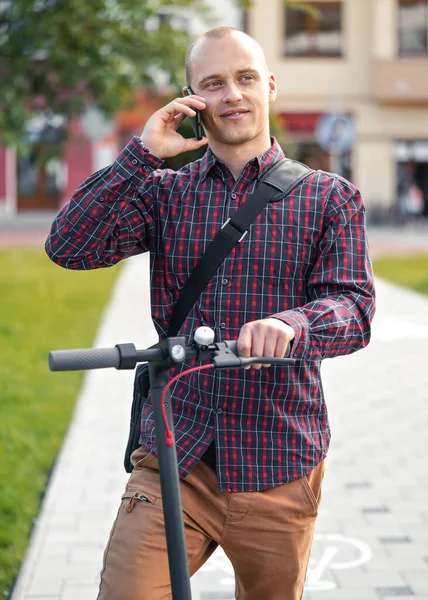 Młody Mężczyzna Luźnych Spodniach Koszuli Stojący Obok Skutera Elektrycznego Rozmawiający — Zdjęcie stockowe