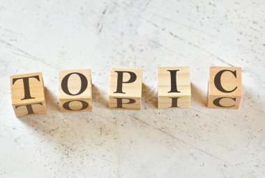Tahta gibi beyaz taş üzerinde TOPIC sözcüğüyle beş tahta küp, yukarıdan görünüm