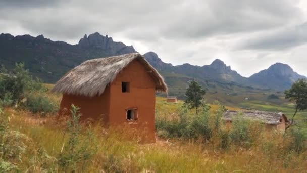 晴れた日には マダガスカルのアンドリンギトラ国立公園での典型的な風景 遠くに水田のあるロッキー山脈 手前に野良屋根の小さな粘土の家 — ストック動画