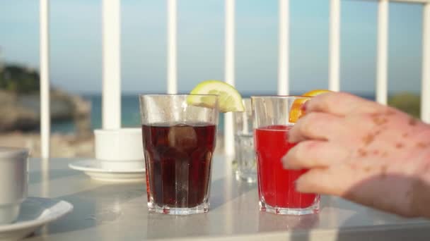 Κόκκινο Ποτό Πορτοκάλι Και Κόλα Ποτήρια Στο Τραπέζι Ηλιόλουστη Παραλία — Αρχείο Βίντεο