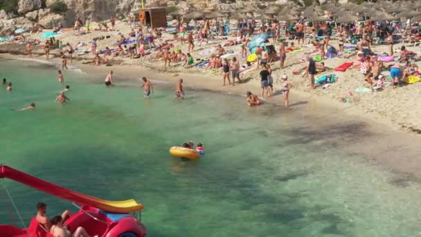 スペインのカレス マリョルカ 2019年9月21日 晴れた夏の日にCala Domingosビーチでリラックスしている人々 そのうちのいくつかは小さな波で海で泳いだり遊んだりしています — ストック動画