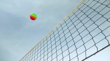 Plaj voleybol ağına, temiz gökyüzüne, gökkuşağı renkli topa bakıyorum.