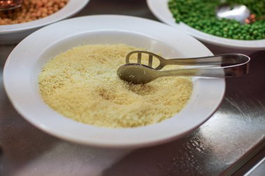 Açık büfede rendelenmiş peynirli beyaz tabak.