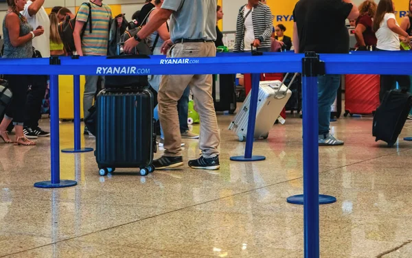 Palma, İspanya - 25 Eylül 2019: Bavulları havaalanında bekleyen yolcular, ayaklarında ve bacaklarında yakın plan detayları, ön planda Ryanair yazısıyla mavi sınır ayırıcısı