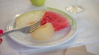 Küçük beyaz tabaktan salamura meyve yiyen genç bir kadın, sadece çatal ve el üzerinde yakın plan detayı.