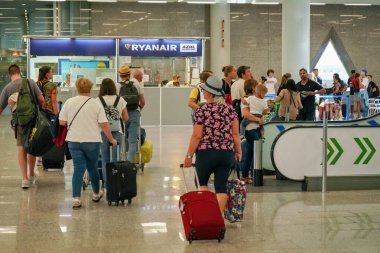 Palma, İspanya - 25 Eylül 2019: Havaalanındaki yolcu vagonlarını çeken turistler yolcu almak üzere çıkış kapısına doğru yürürken, Ryanair müşteri bilgilendirme arkaplanı