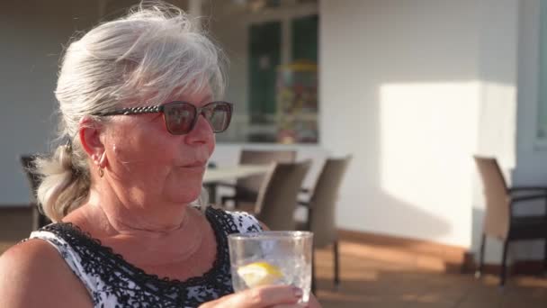 Oudere Oudere Vrouw Strand Hoed Drinken Uit Glas Wazig Hotel — Stockvideo