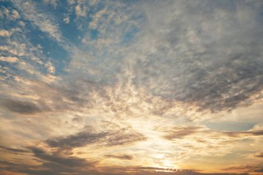 Sabah mavi turuncu gökyüzü, güneş bulutların arasında parlıyor.