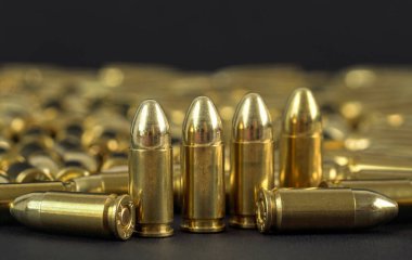 Siyah masa üzerinde bir sürü pirinç tabanca mermisi yakın çekim görüntüsü,