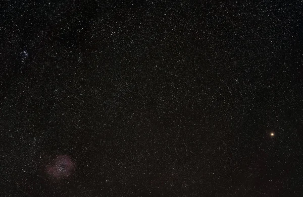 多くの星を持つ冬の夜空 左下隅に見えるロゼット星雲 右側に明るい黄色のベテルギウス星 — ストック写真